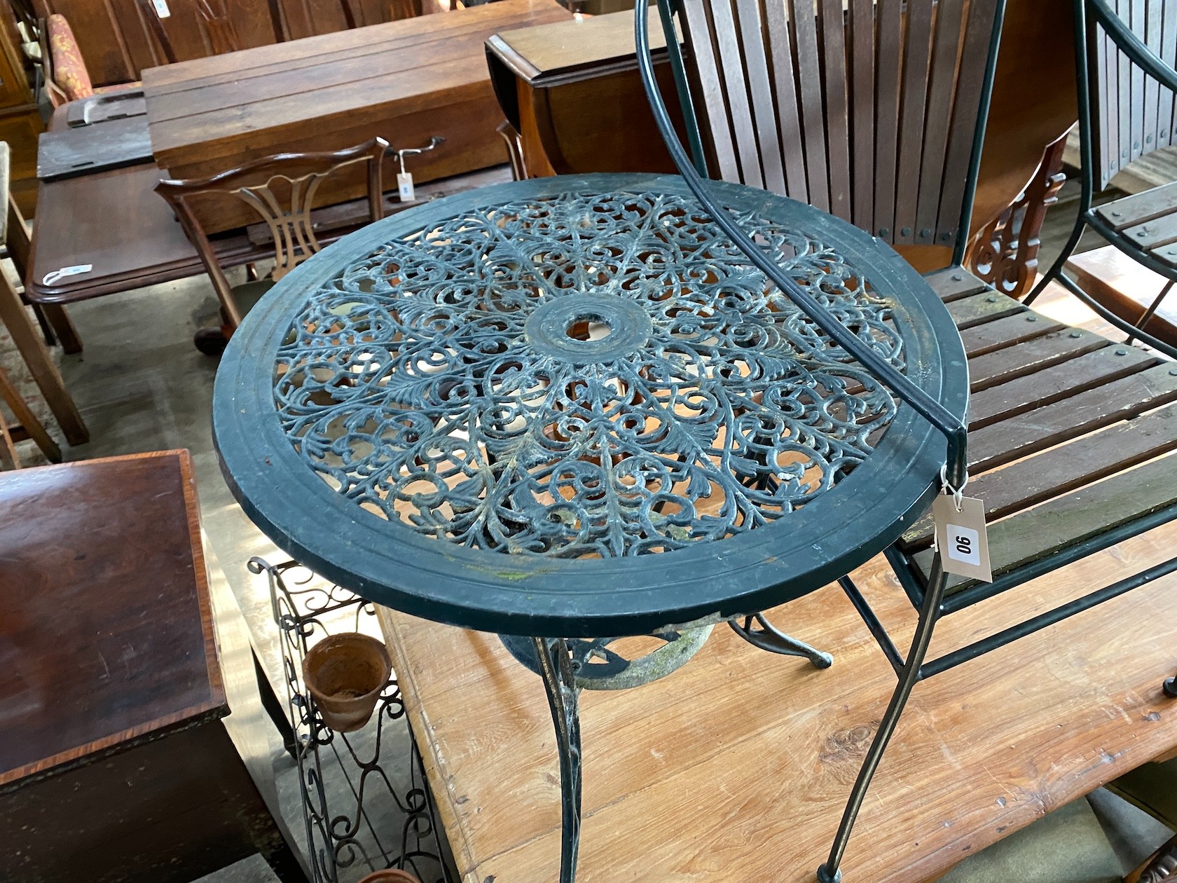 Two wrought iron slatted garden chairs, a circular table and a wrought iron pot stand